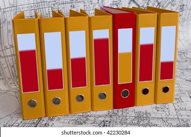 Row from the yellow file folders and one red folder with clean blanks for your text. Black and white project drawings are background - Powered by Shutterstock