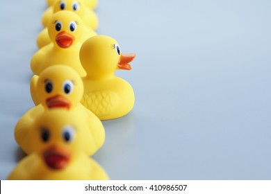 A row of yellow rubber ducks with one of the ducks facing in a different direction all the other duck are facing. The focus is on the duck facing in a different direction. - Shutterstock ID 410986507