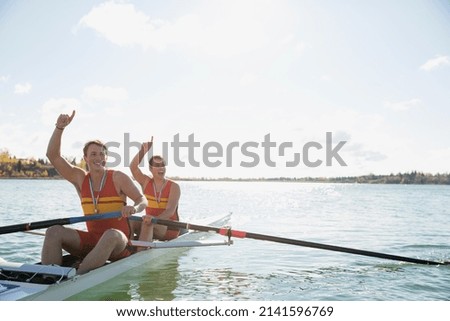 Rowers celebrating in scull on sunny river