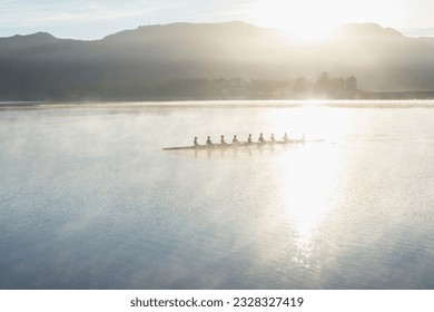 Rowing team rowing boat on still lake - Powered by Shutterstock