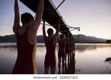 Rowing team carrying boat overhead into lake - Powered by Shutterstock