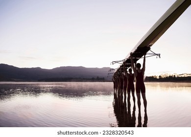 Rowing team entering lake at dawn with scull overhead - Powered by Shutterstock