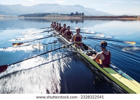 Rowing team rowing scull on lake