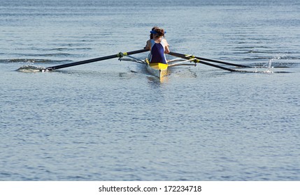 Rowing Team Working In Unison To Compete In A Regatta By Racing Specially Built Row Boats