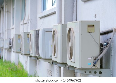Rows of air conditioning units on concrete wall.