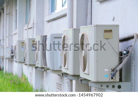 Rows of air conditioning units on concrete wall.