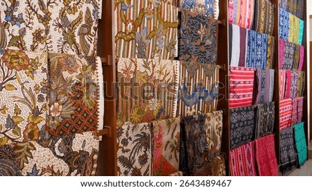 Rows of batik cloth in various colors in a shop