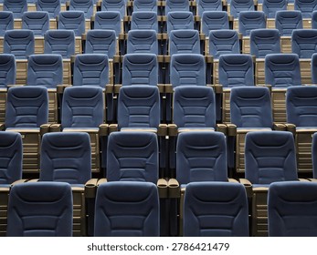 Rows of blue seats in an empty auditorium. Uniform seating with wooden armrests and backrests. Clean, orderly arrangement facing forward. Ideal for event or venue settings
