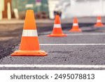 Rows of bright orange traffic cones placed on the asphalt road at a construction site road repairs