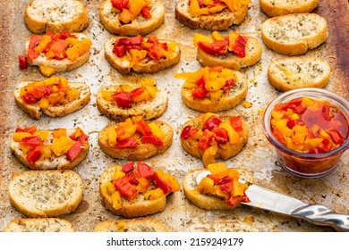 Rows of bruschetta toasts spread with gourmet peppers and oil mix food preparation scene