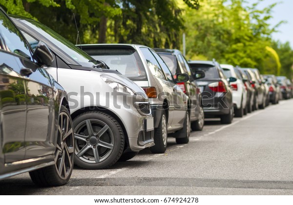 Rows of cars parked on the\
roadside in residential district. Small car parked between other\
cars.