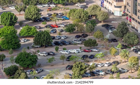 Rows Of Cars Parked In A Parking Lot Between Lines Of Green Leafy Trees Viewed From Overhead From Above Timelapse During All Day With Shadows Moving Fast. Aerial View Of Residential District In Dubai