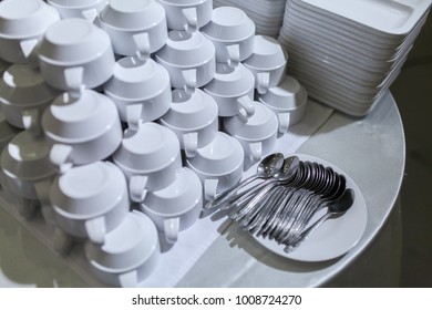 Rows of clean white upside down cups, dish and spoon in a cafeteria or restaurant ready to serve a hot beverage