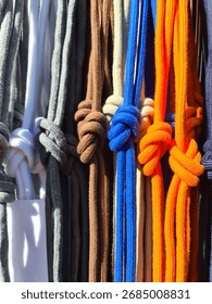 Rows of colorful drawstrings hanging vertically, showing various hues and knotted ends. Textile texture creating patterns