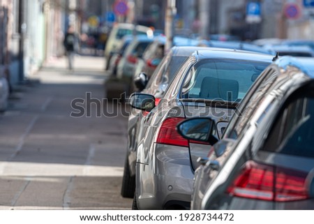 rows of different cars parked along the roadside in crowded city, close-up, selective focus