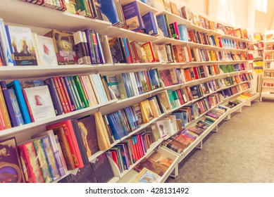 Rows of different colorful books lying on the shelves in the modern urban bookshop