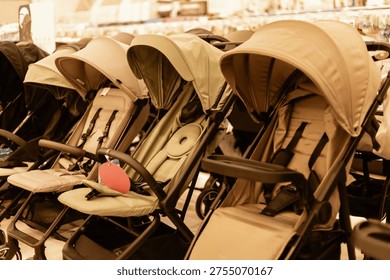 Rows of different types of strollers are set up in a store. Families can browse the selection. Each stroller has a different style and color for customers to choose from