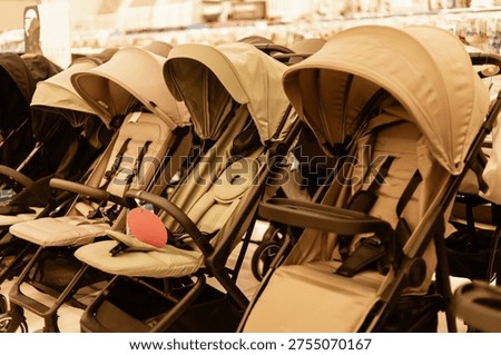 Rows of different types of strollers are set up in a store. Families can browse the selection. Each stroller has a different style and color for customers to choose from