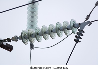Rows of electrical wires with insulators mounted on bars at high voltage electrical substation against blue sky
