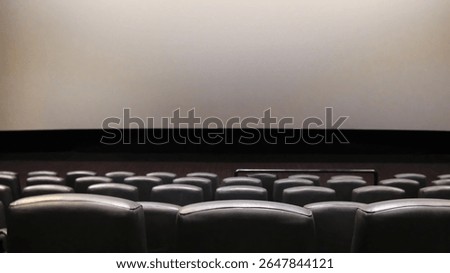 Rows of empty black leather cinema seats in a modern movie theater