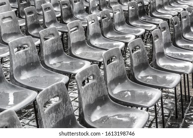 Rows of empty gray chairs in the rain, background.