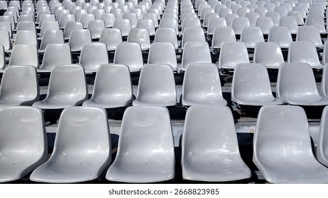 Rows of empty grey plastic seats and stairs in a outdoor festival scene during a bright afternoon. Mobile scene cocnept.