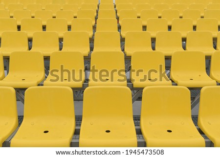 Rows of empty place in the stadium. Plastic seats in yellow.