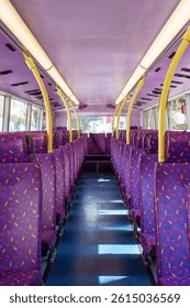 Rows of empty purple seats inside a hong kong double-decker bus, creating a vibrant and colorful interior
