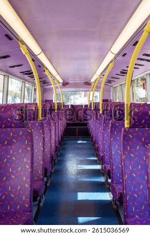 Rows of empty purple seats inside a hong kong double-decker bus, creating a vibrant and colorful interior