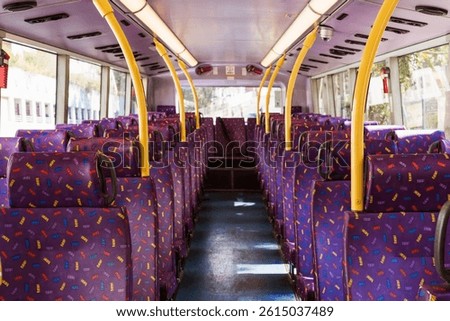 Rows of empty purple seats inside a hong kong double-decker bus, creating a vibrant and colorful interior