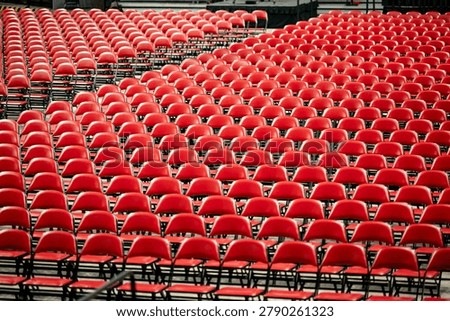 Rows of empty red chairs prepared for a large event, ceremony, graduation, or public gathering inside an arena