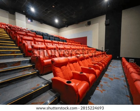 Rows of empty red leather seats in a modern cinema hall
