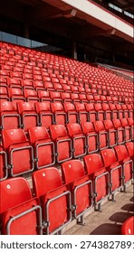 Rows of empty red plastic seats fill the grandstand of a modern sports stadium, waiting for fans to arrive for the game.
