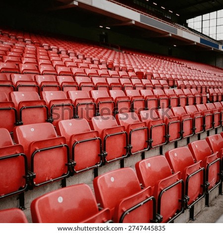 Rows of empty red plastic seats in a large outdoor stadium stand ready for spectators before a major sporting event or match.