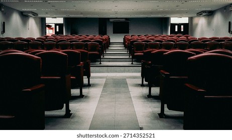 Rows of empty red seats in a large modern lecture hall or theater.