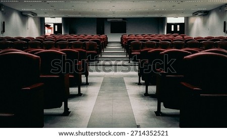 Rows of empty red seats in a large modern lecture hall or theater.