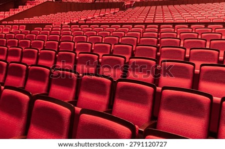 Rows of empty red seats in a theater auditorium