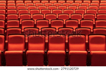 Rows of empty red seats in a theater auditorium