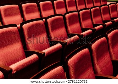 Rows of empty red seats in a theater auditorium