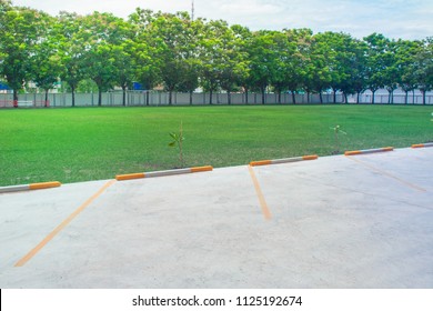 Rows Of Empty Space Car Parking Lot At Outside Beside Green Grass Meadow Soccer Field. (Selective Focus)