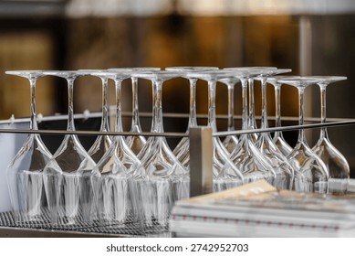 Rows of empty wine glasses on table in modern restaurant Wine glasses hanging upside down on rack in modern restaurant or cafe interior