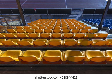 Rows of empty yellow plastic seats at sports stadium