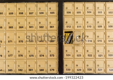 Rows of gold post office boxes with one open mail box.