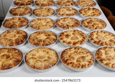 Rows of golden brown bread rolls freshly baked and cooling on surface in busy bakery kitchen. Aroma of freshly baked goods fills air. - Powered by Shutterstock