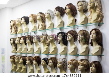 Rows of hair wigs on display, on some dummies, in a store.
