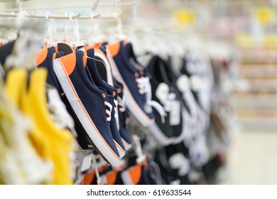 Rows of hangers with sneakers of different colours in shoes store on blurry background