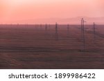 Rows of high-voltage power lines at sunset or sunrise in Charyn Canyon National Park in the Almaty Province of Kazakhstan.