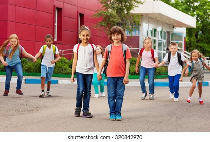 Rows of kids with rucksacks near school walking