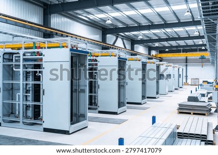 Rows of large, empty electrical control panels and distribution boxes are neatly arranged on the factory floor, ready for installation