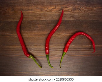 The Rows Of Long Red Chilli Peppers On The Wood Pattern Background.